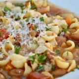 Un plato humeante de pasta e fagioli, con tiernos macarrones, alubias, trozos de tomate y un toque de queso rallado.