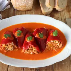 Pimientos del piquillo rellenos de atún y huevo, bañados en una salsa de pimientos. Un plato casero listo para disfrutar.