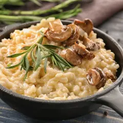 Cremoso arroz italiano con champiñones y romero, servido en sartén de hierro fundido.