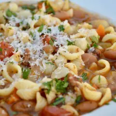 Un plato humeante de pasta e fagioli, con tiernos macarrones, alubias, trozos de tomate y un toque de queso rallado.