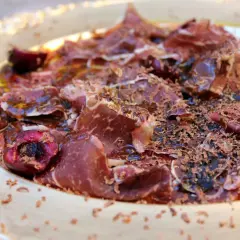 Deliciosa cecina con aceite, cerezas y virutas de chocolate. Un plato sorprendente y lleno de sabor.