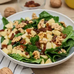 Deliciosa ensalada de espinacas con trozos de manzana, pasas y nueces crujientes.