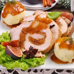 Rollo de cerdo relleno, servido con puré de patatas y salsa. Un plato festivo que recuerda a un cerdo trufero, decorado con higos y adornos navideños.