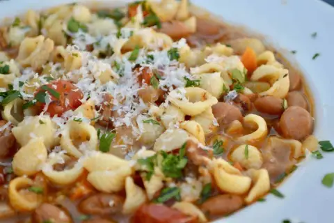 Un plato humeante de pasta e fagioli, con tiernos macarrones, alubias, trozos de tomate y un toque de queso rallado.