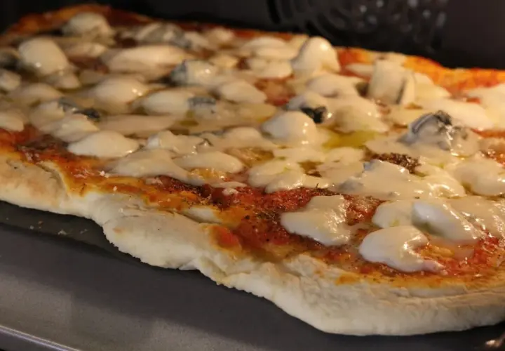Pizza 4 formaggi recién salida del horno, con queso fundido y trozos de queso azul.