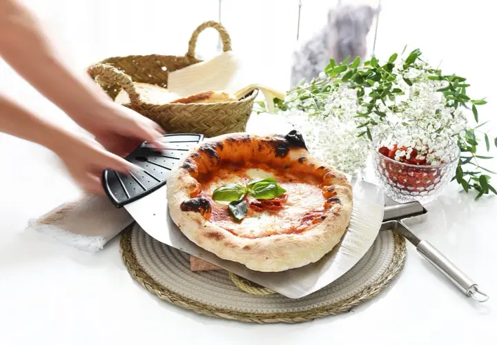 Manos estirando masa de pizza. Pizza recién horneada con albahaca y tomates secos, lista para servir.