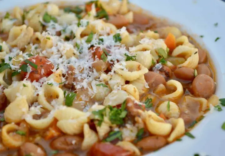 Un plato humeante de pasta e fagioli, con tiernos macarrones, alubias, trozos de tomate y un toque de queso rallado.