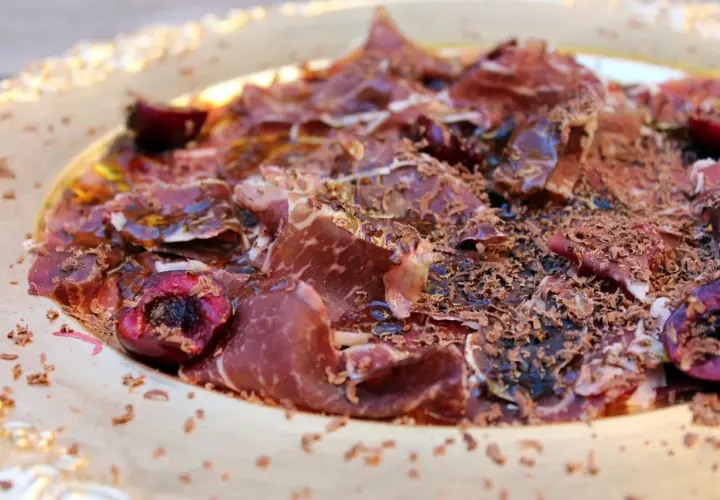 Deliciosa cecina con aceite, cerezas y virutas de chocolate. Un plato sorprendente y lleno de sabor.