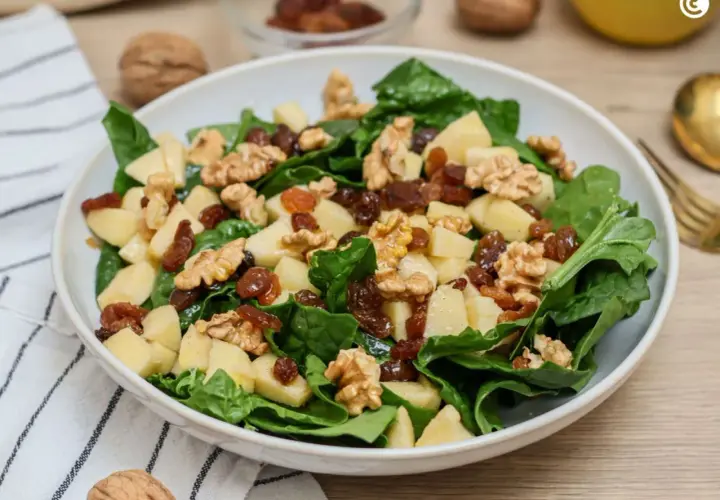 Deliciosa ensalada de espinacas con trozos de manzana, pasas y nueces crujientes.