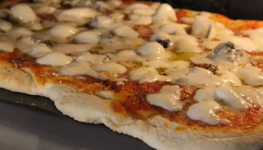 Pizza 4 formaggi recién salida del horno, con queso fundido y trozos de queso azul.