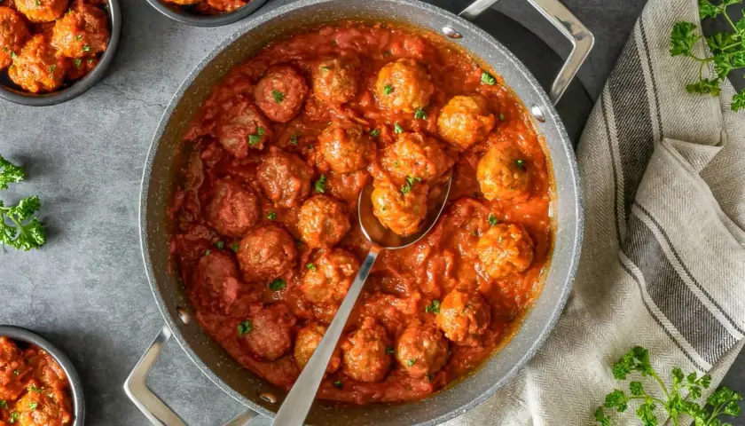 Sabrosas albóndigas caseras en una rica salsa de tomate, servidas en una sartén y cuencos.
