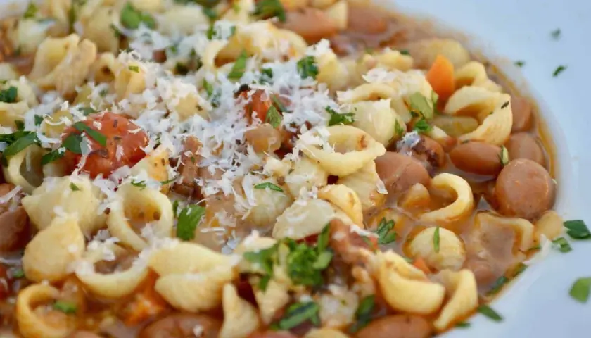 Un plato humeante de pasta e fagioli, con tiernos macarrones, alubias, trozos de tomate y un toque de queso rallado.