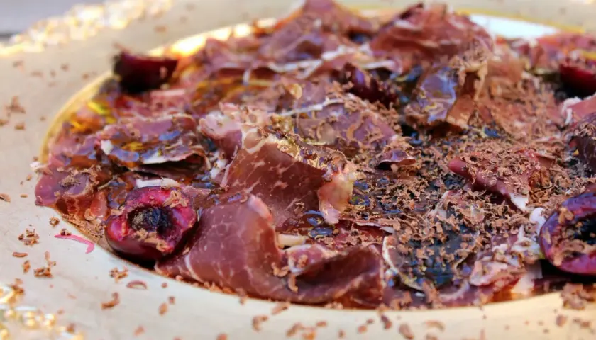 Deliciosa cecina con aceite, cerezas y virutas de chocolate. Un plato sorprendente y lleno de sabor.