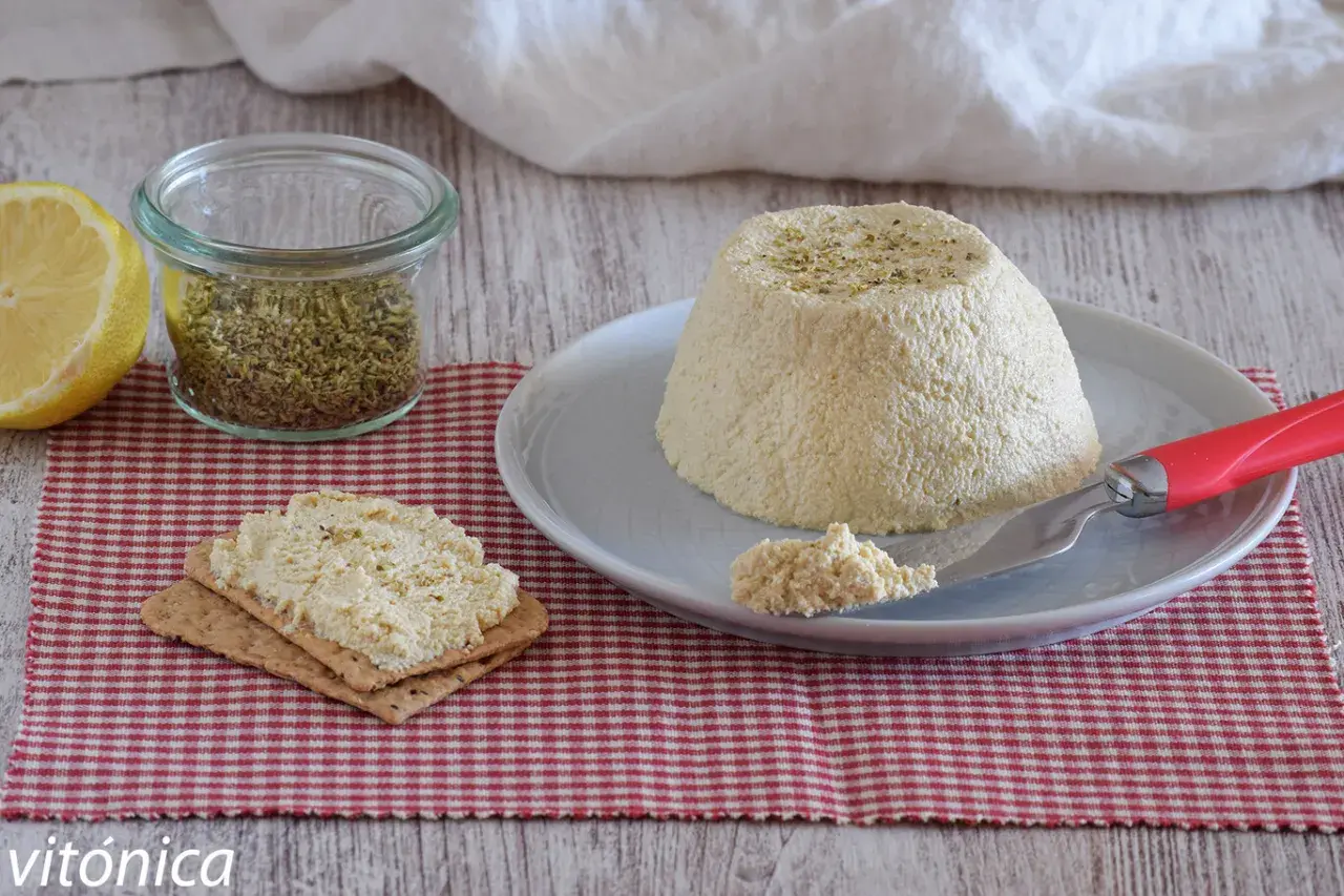 Deliciosa ricotta vegana con hierbas, servida en un plato con galletas y limón.