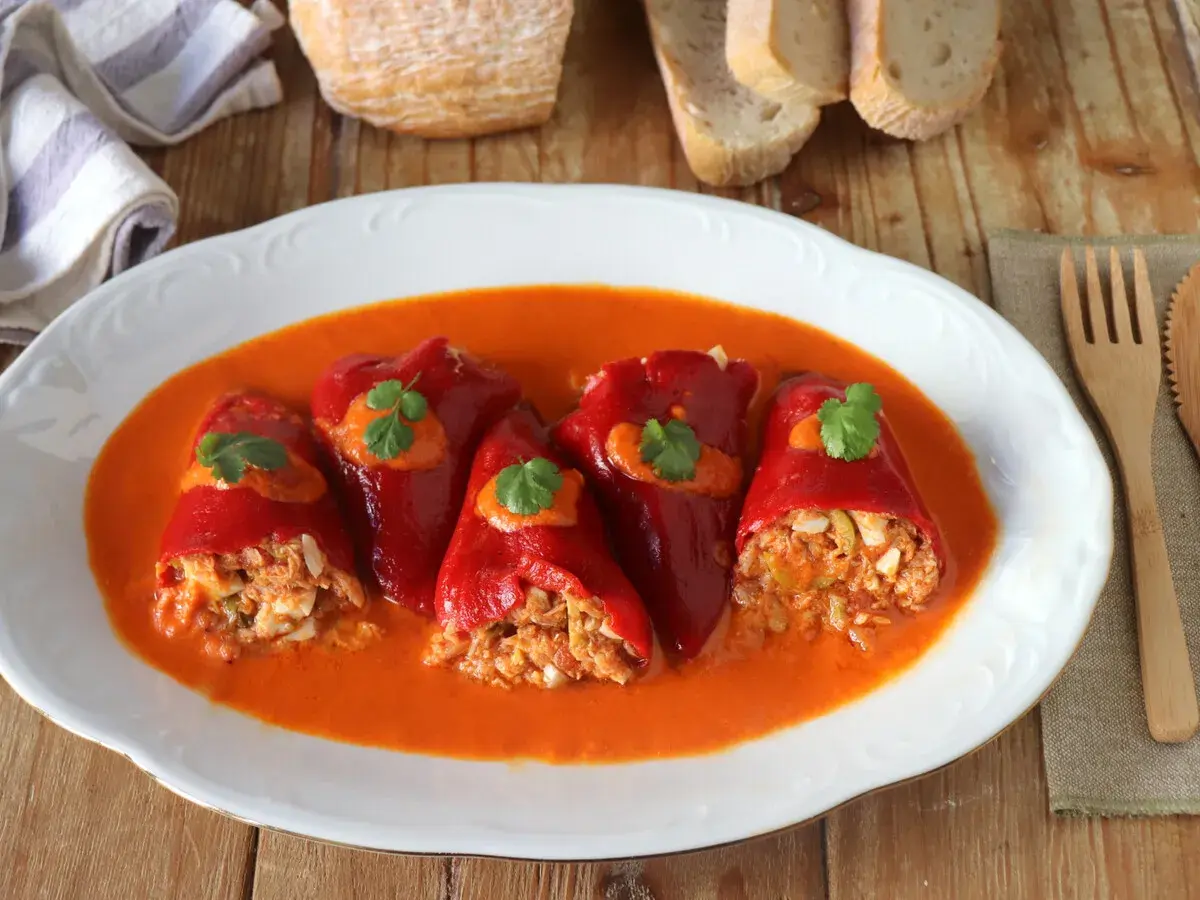 Pimientos del piquillo rellenos de atún y huevo, bañados en una salsa de pimientos. Un plato casero listo para disfrutar.