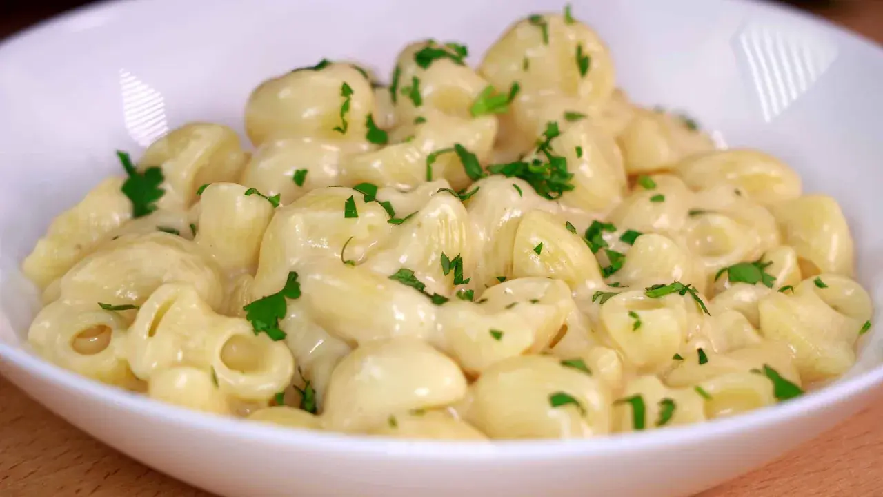 Mac and cheese cremoso, con trozos de perejil fresco espolvoreados. Un plato reconfortante y delicioso.