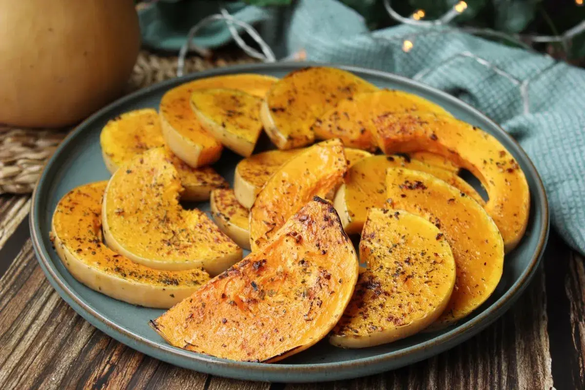 Rodajas de calabaza a la plancha, doradas y sazonadas con hierbas, servidas en un plato azul.