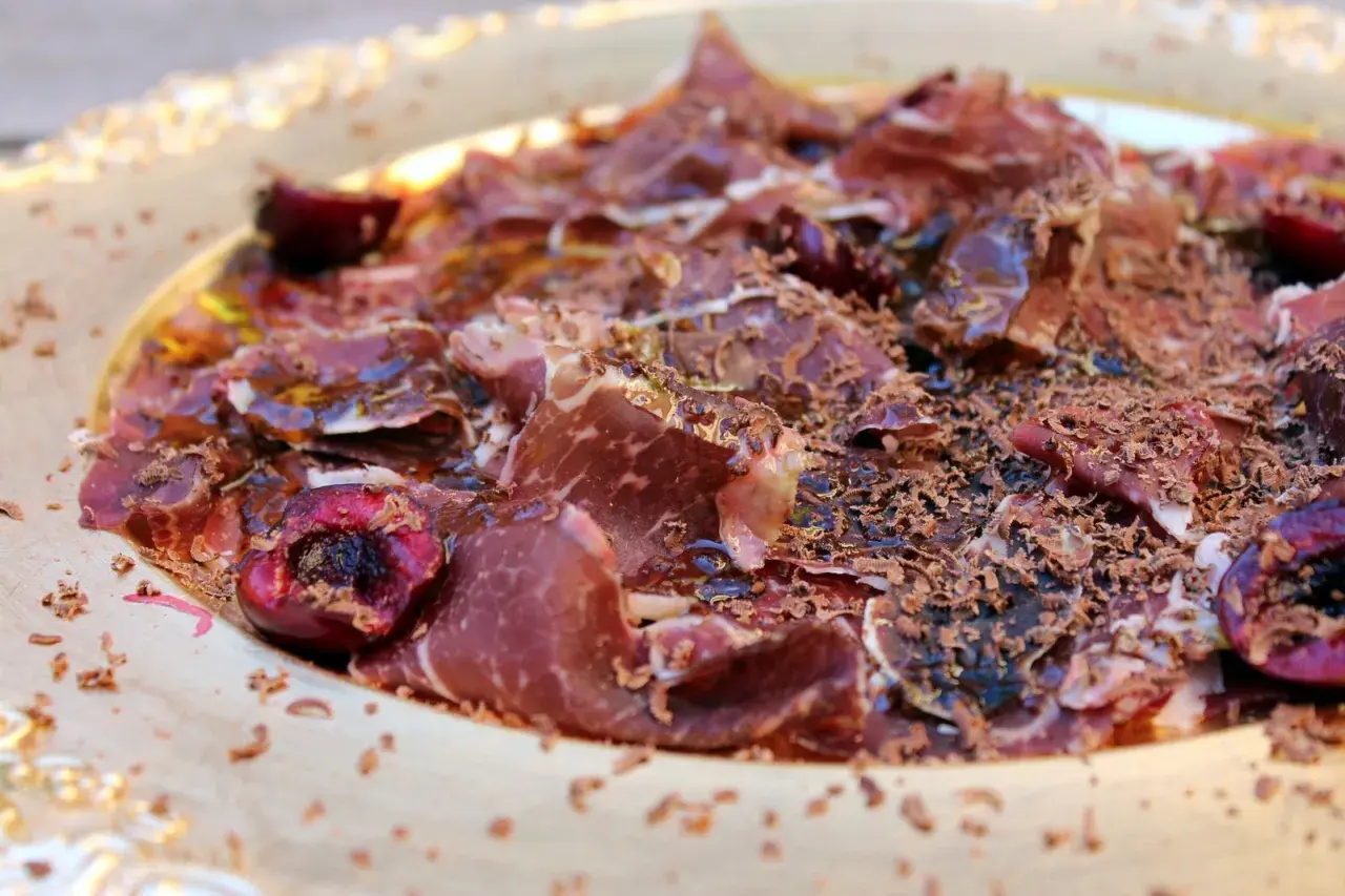 Deliciosa cecina con aceite, cerezas y virutas de chocolate. Un plato sorprendente y lleno de sabor.
