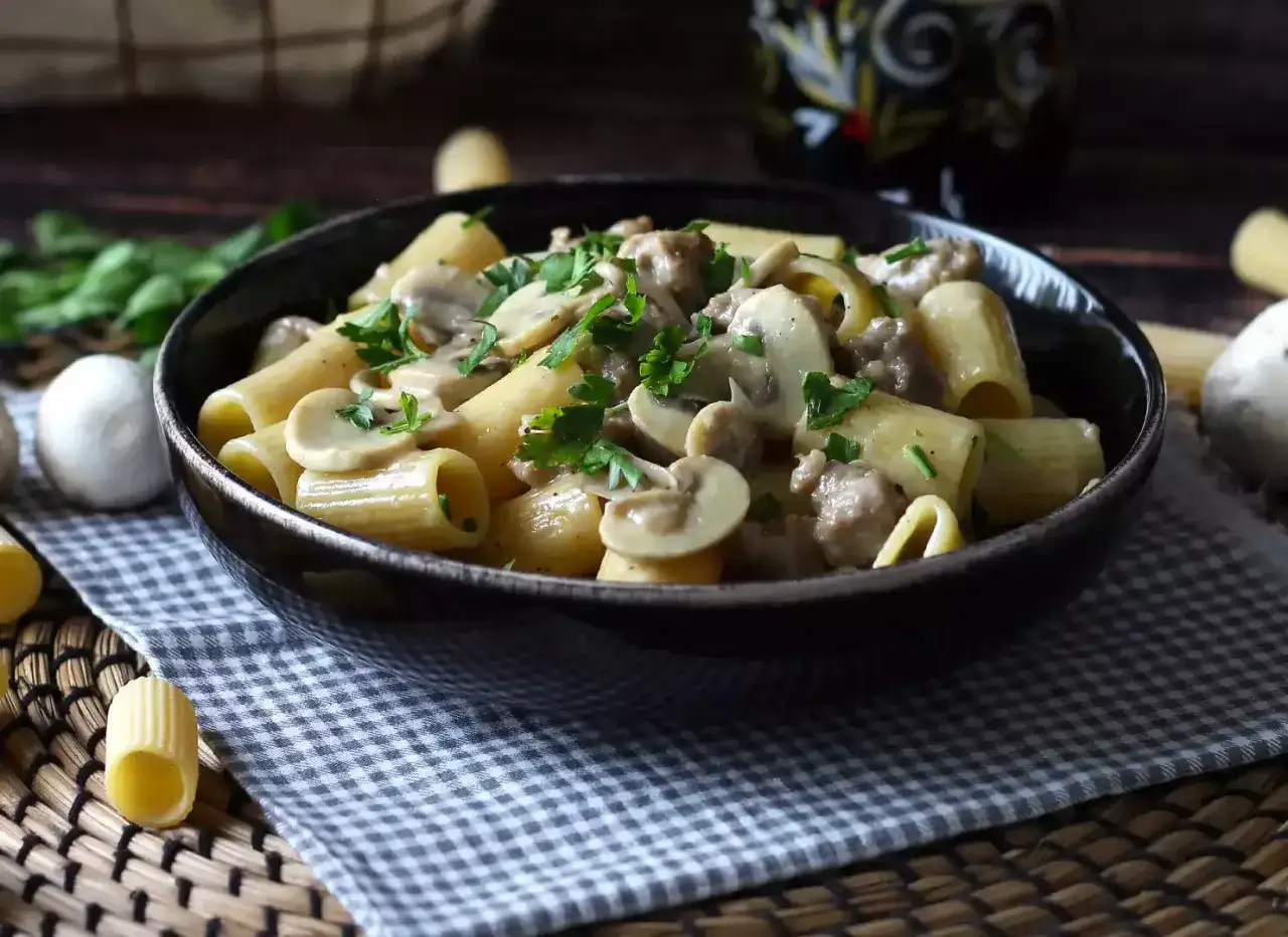 Pasta con burrata y champiñones, cremosa y deliciosa, servida en un cuenco oscuro con perejil fresco.
