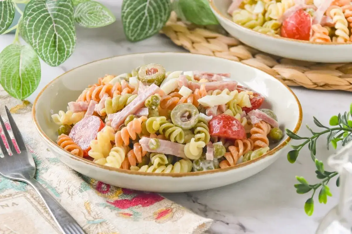 Ensalada de pasta espectacular con fusilli tricolor, jamón, huevo duro, aceitunas y guisantes. ¡Un plato fresco y delicioso!