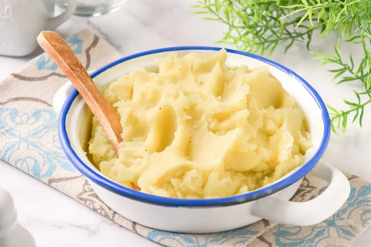 Un cremoso parmentier de patata, listo para servir, con una cuchara de madera incrustada.