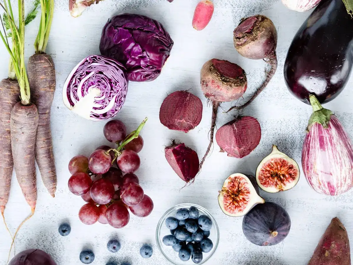 Un surtido de verduras raras y frutas moradas: zanahorias, col, remolachas, berenjenas, higos, uvas y arándanos.