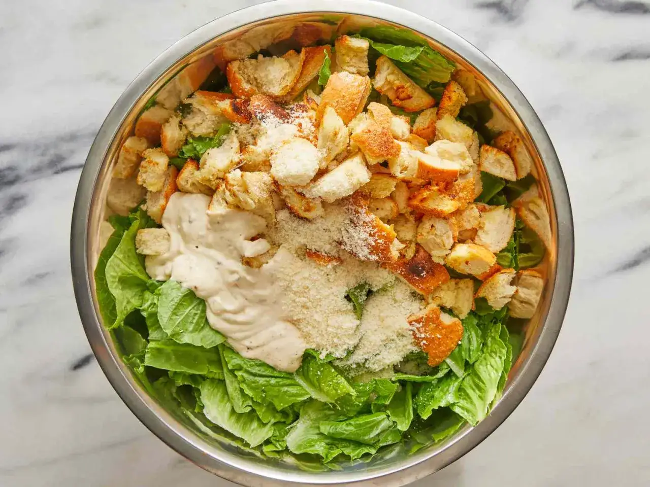 Ensalada C&eacute;sar en un bol de metal, con lechuga romana, picatostes crujientes, queso rallado y una cremosa salsa C&eacute;sar.