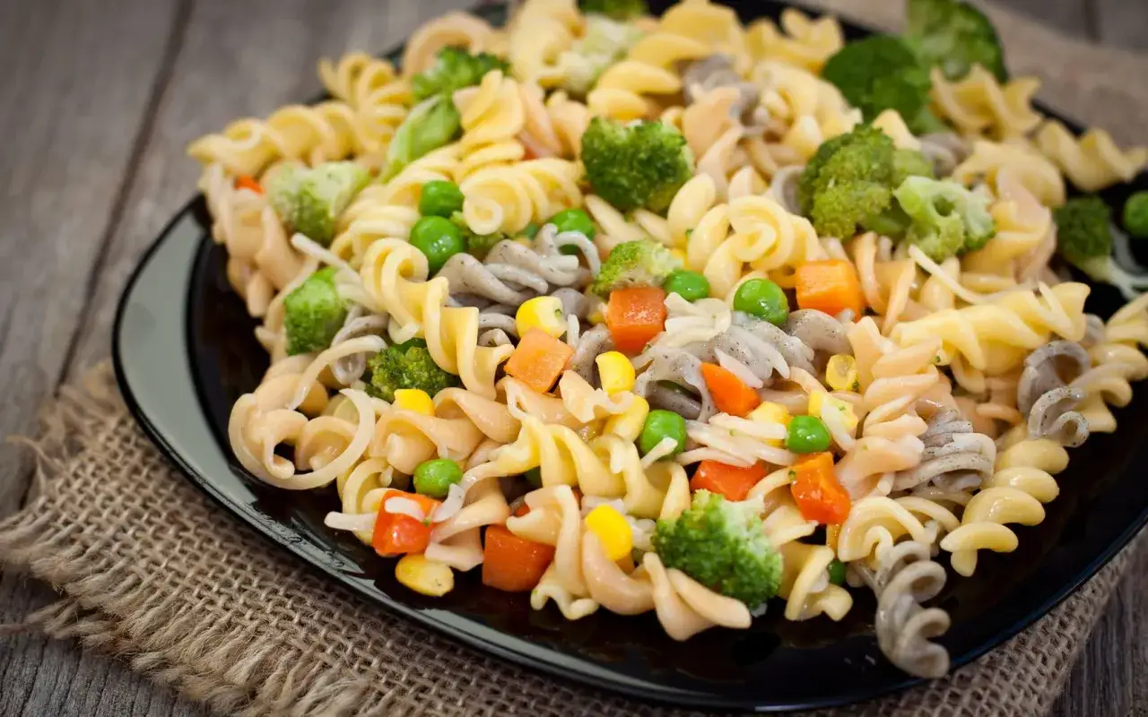 Deliciosa ensalada de pasta vegana con brócoli, guisantes, zanahoria y maíz.