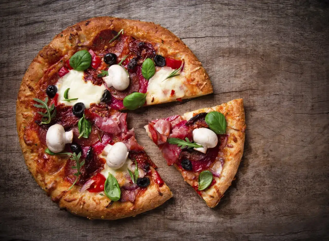 Pizza casera con champiñones, aceitunas y albahaca sobre madera rústica. ¡Perfecta para aprender como hacer pizza casera!
