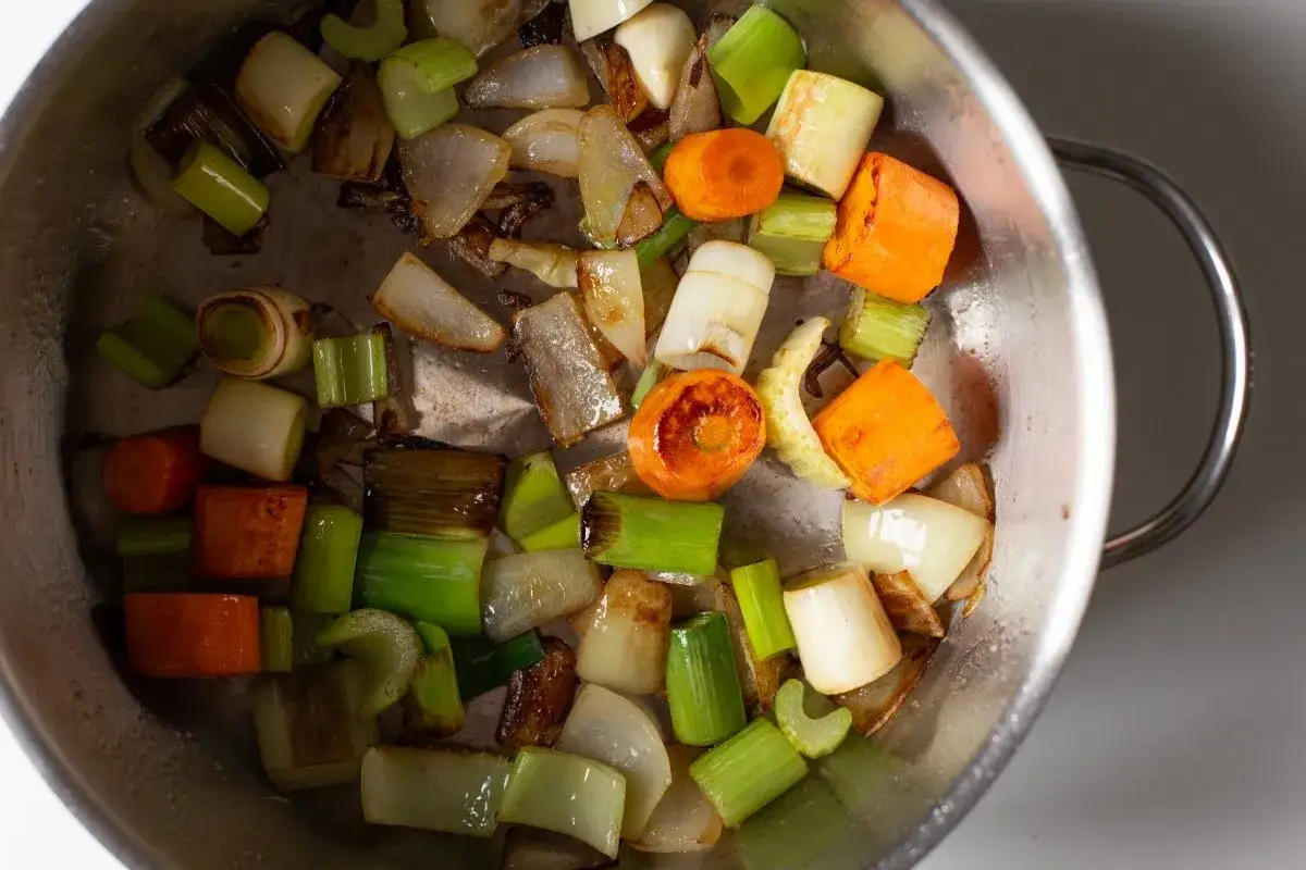 Verduras cortadas en trozos (zanahoria, apio, puerro, cebolla) en una olla, listas para hacer un sabroso caldo de verduras.