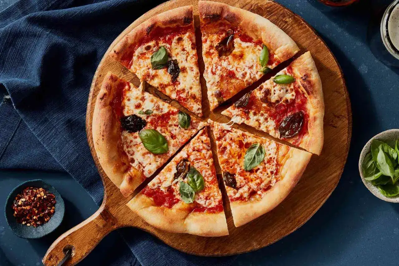 Pizza margarita recién horneada, con queso derretido, salsa de tomate y hojas de albahaca fresca, lista para ser disfrutada.