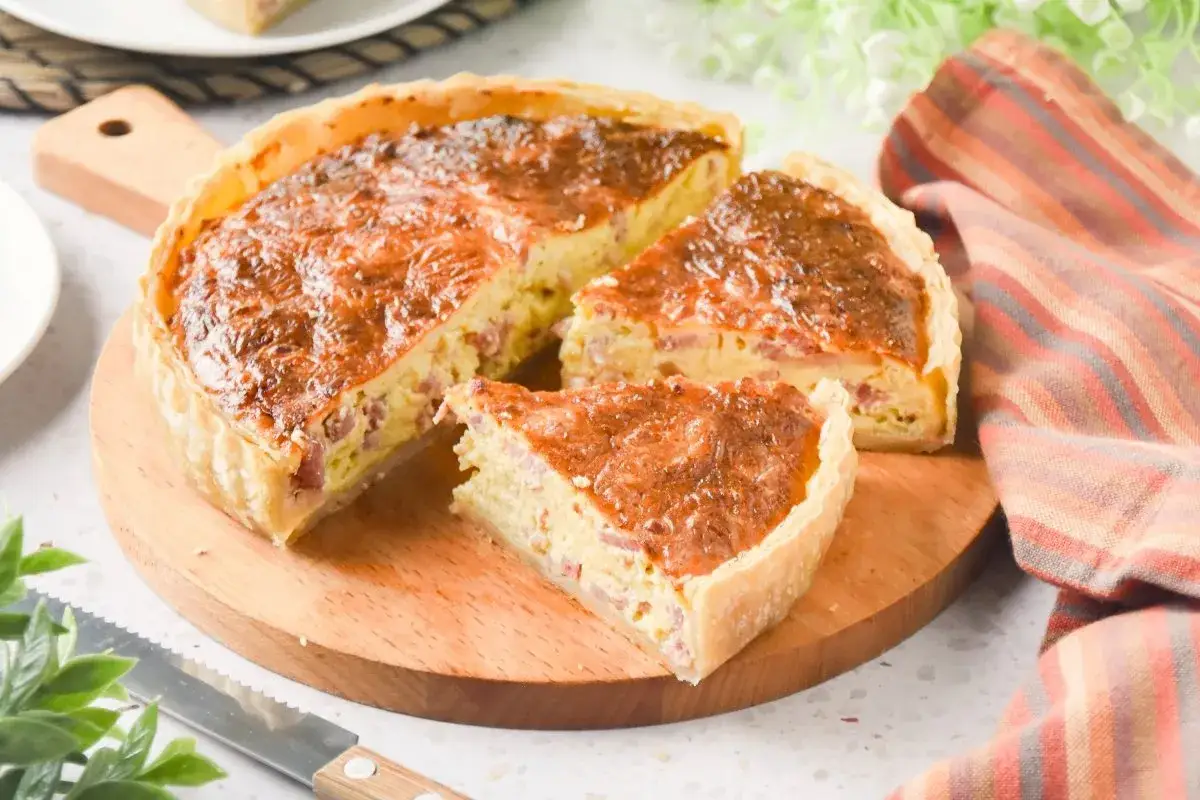 Un delicioso quiche de bacon, reci&eacute;n horneado y cortado en porciones, listo para disfrutar.