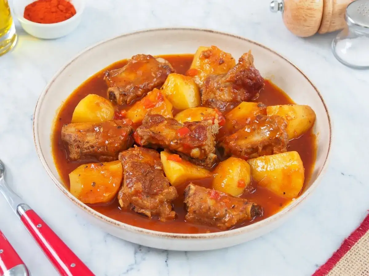 Un plato humeante de costillas guisadas de la abuela con patatas tiernas en una rica salsa roja.