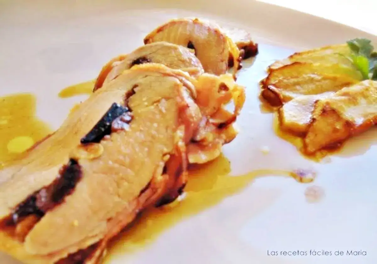 Rodajas de cerdo trufero jugoso, con trozos oscuros de trufa incrustados, servidas en un plato blanco con salsa dorada.