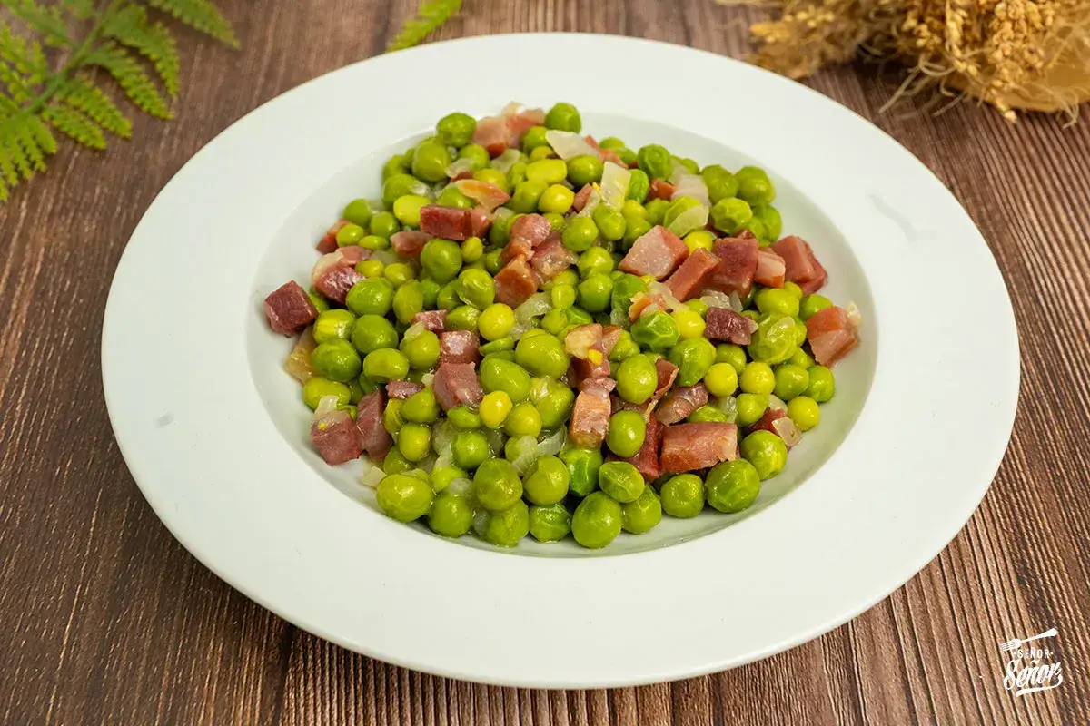 Guisantes con jamón, un plato sencillo y delicioso. Los guisantes verdes se mezclan con trozos de jamón salado y cebolla picada.