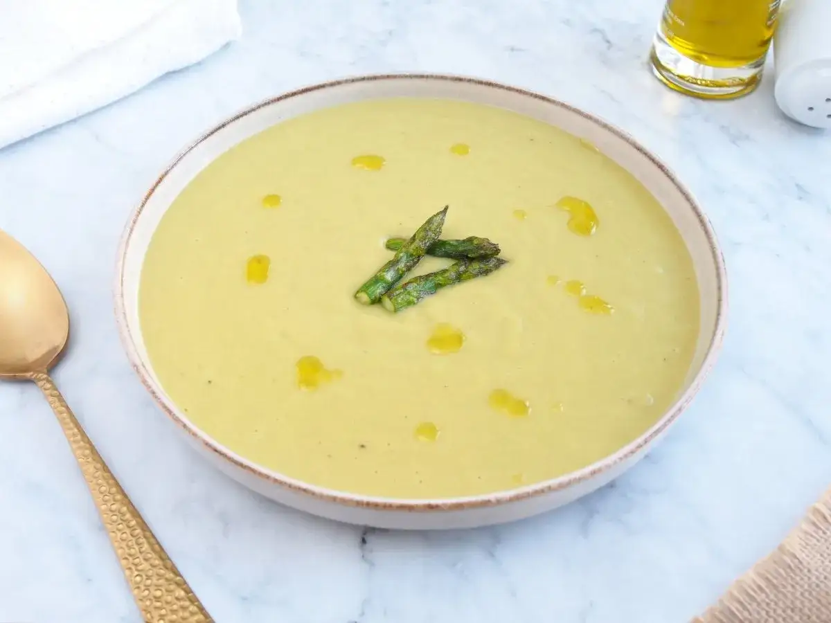 Crema de espárragos suave y sedosa, decorada con espárragos tiernos y un chorrito de aceite de oliva.