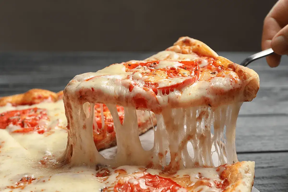 Una rebanada de pizza con queso para pizzas fundido y estir&aacute;ndose.
